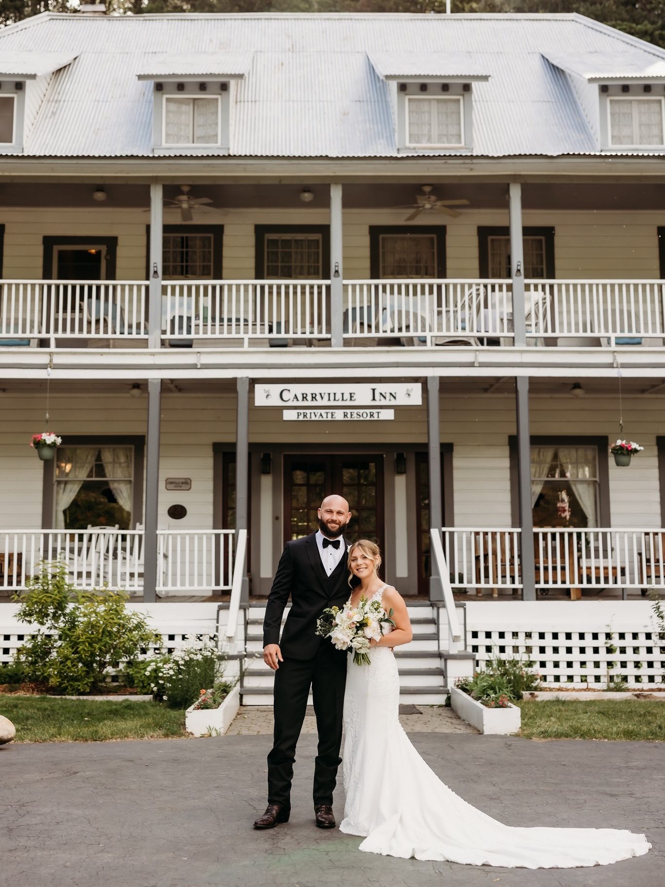 Kelsey and Colton smiling together in front of the Carrville Inn Private Resort sign on their wedding day