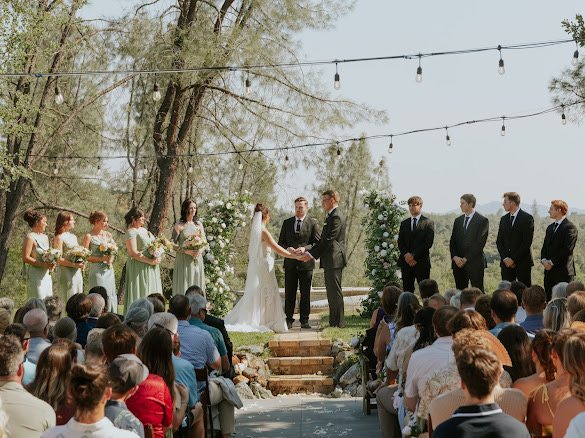Dylan and Faith exchanging vows at the fountain altar as bridesmaids, groomsmen, and guests look on